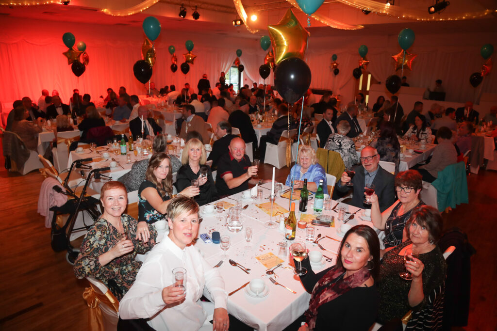 A group of people sat at a table smiling for a photograph at the Star Awards 2022